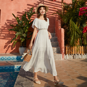 Off-shoulder frill maxi dress with summer-ready design, woman in white dress and hat by a pool.